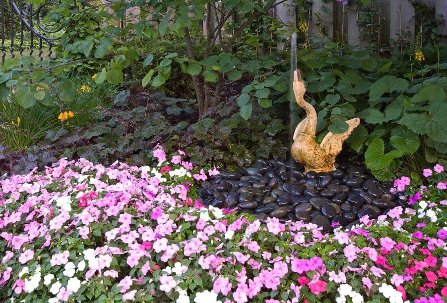 fountain shaped like a goose with mexican black pebbles and impatiens