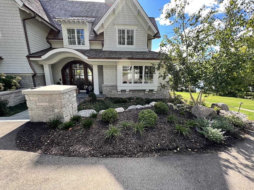 Before renovation view of a lakeside home front yard in Williams Bay, Wisconsin, showing limited landscaping and minimal planting design.